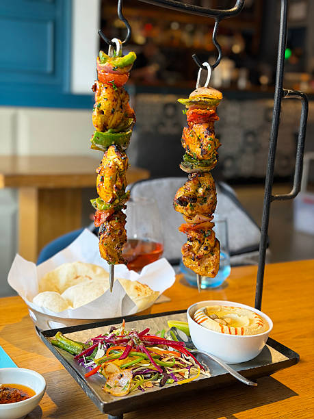 Image of hanging chicken shish taouk kebab with Turkish greek hummus, warm pitta bread and fresh salad, authentic Mediterranean street food presentation