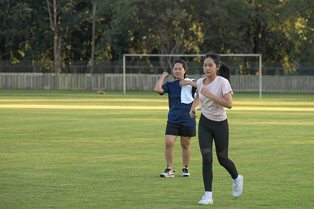 Two people exercising outdoors, jogging together on a green grass field during a sunny afternoon.