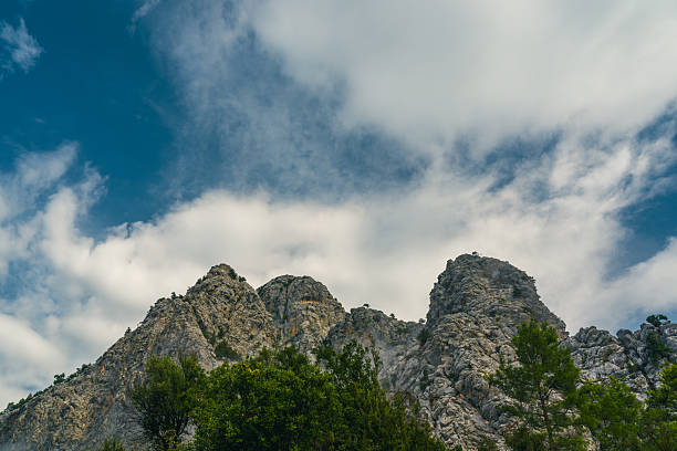 Rugged rocky mountain peaks rising sharply beneath dynamic clouds