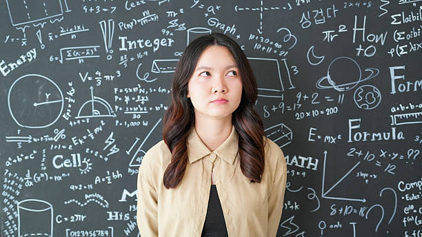 istock Young woman with serious expression against blackboard filled with mathematical equations and educational concepts 2251817022