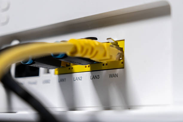 istock White internet router's back panel showing yellow and black Ethernet cables plugged into LAN and WAN ports, essential for fast, reliable home and office network connections 2251819761