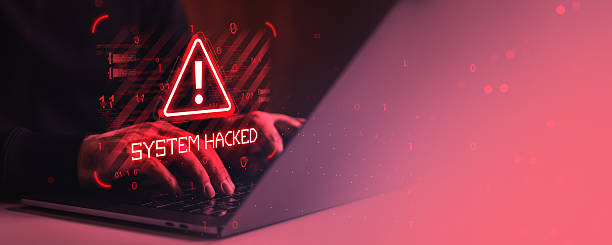 istock Cybersecurity warning with system hacked alert on laptop screen and hands typing in dark red digital environment with binary code overlay. 2251819922