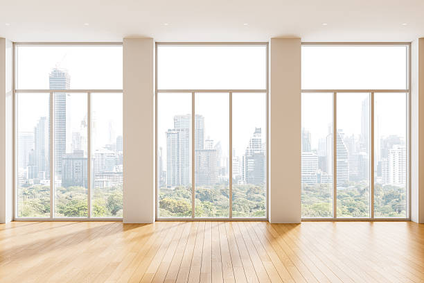 istock Modern interior design concept in empty room with panoramic city view and wooden floor through large glass windows in bright daylight setting. 3D Rendering 2251820012