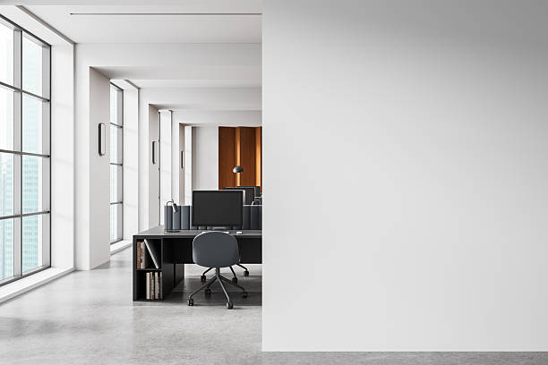 istock Modern office interior with computer desks and large empty white wall for poster or banner mockup in clean bright workspace layout template concept. 3D Rendering 2251821415