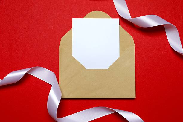 istock Beautiful white silk ribbon and paper envelope on red background, space for text 2251821598