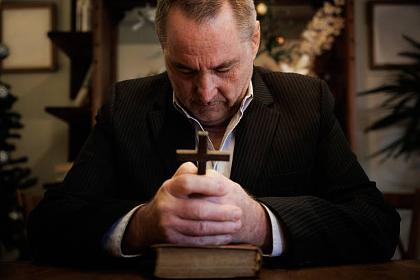 Front view man praying alone in church sitting in pew