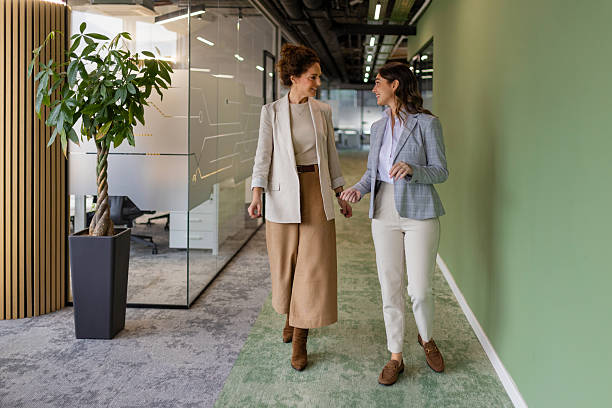 istock Two Businesswomen Walking and Talking in Modern Office Hallway 2251824372