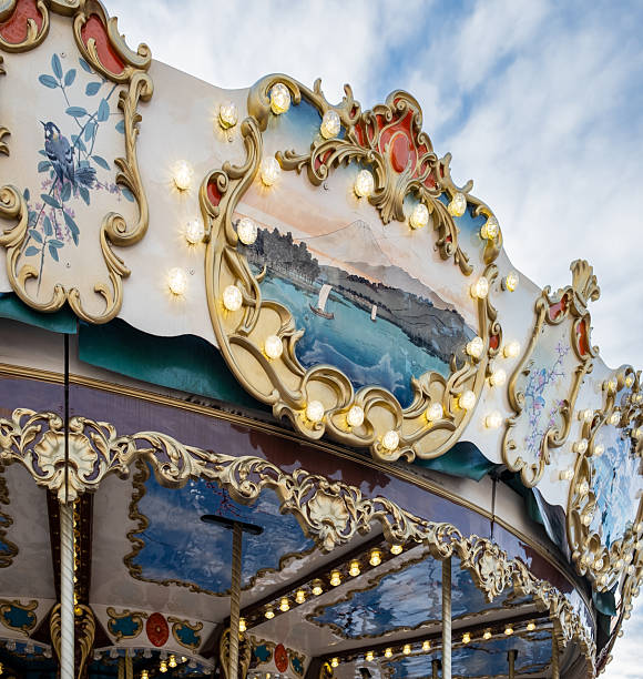 Low angle shot of a classic carousel with glowing lights. Ornate vintage details shine against a beautiful sky, evoking joy and nostalgia. Perfect for festive and travel concepts.