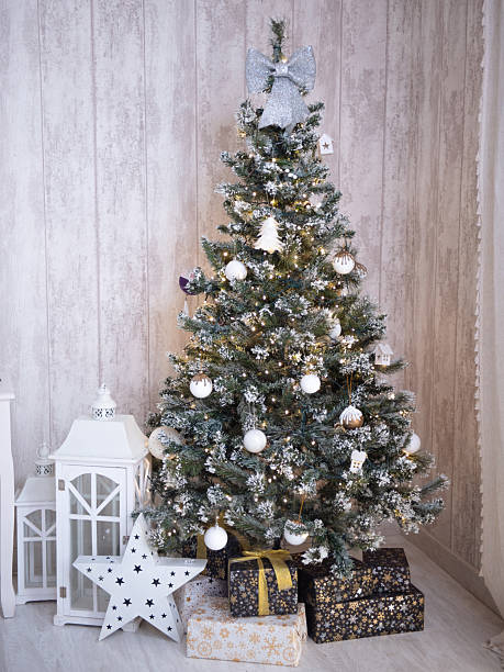 istock Festively decorated Christmas tree adorned with white ornaments and a silver bow, surrounded by beautifully wrapped gifts and lanterns, creating a cozy holiday atmosphere 2251832136