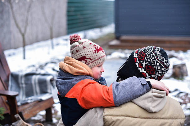 Son and father in winter clothes hugging and smiling while sitting outside