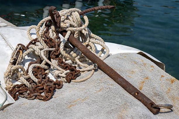 Old big rusted anchor with a chain and rope on the coast of Ionian sea. Diagonal line of the coast and water. Kerkyra, Corfu (Korfu), Greece.