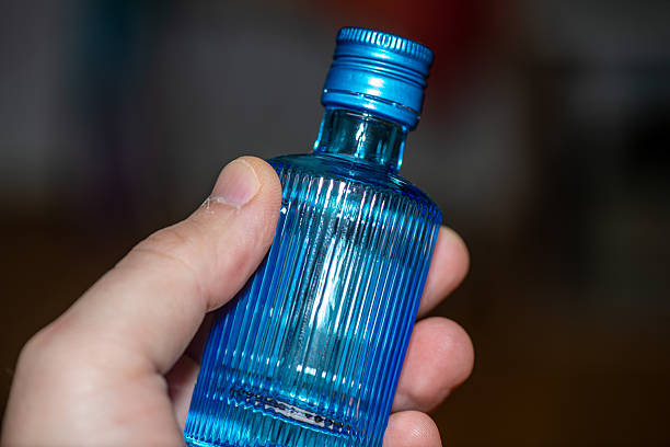A detailed close-up photograph of a hand holding a small blue glass vial, showcasing its smooth texture, transparency, and clean product aesthetic. Perfect for medical, laboratory, cosmetic, and pharmaceutical themes.