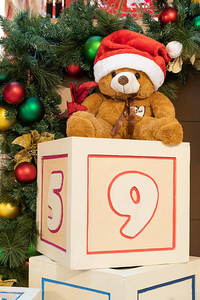 Cute Teddy Bear with Santa hat on Christmas blocks beside festive tree decoration