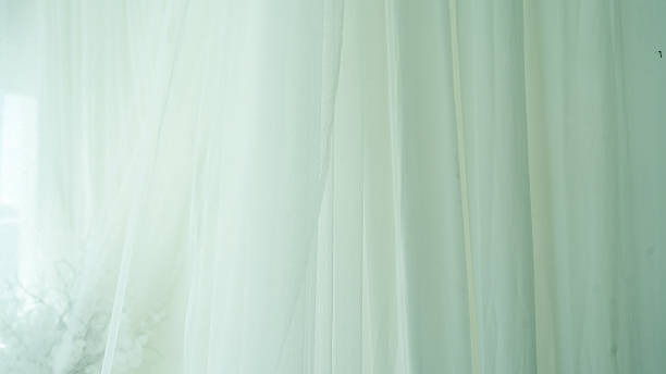 Soft, flowing white fabric drapes gracefully, creating ethereal atmosphere. delicate texture and light transparency evoke sense of calm and elegance, perfect for serene setting
