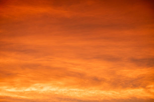 Colorful sunset sky with warm orange and purple clouds creating a dramatic natural background. Soft gradient evening light for nature, travel, landscape and abstract design use, beautiful dark sky