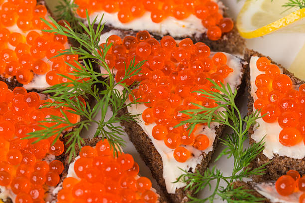 Rye bread with butter and red caviar with lemon and dill as a sandwich. Macro. Photo can be used as a whole background.