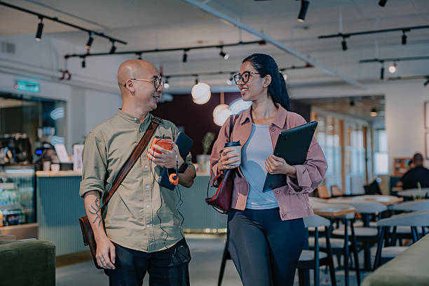 istock Two asian professionals walking and talking in a modern coworking space 2251849652