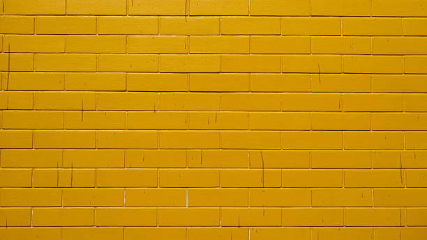 istock Vibrant Yellow Painted Brick Wall Background 2251850731