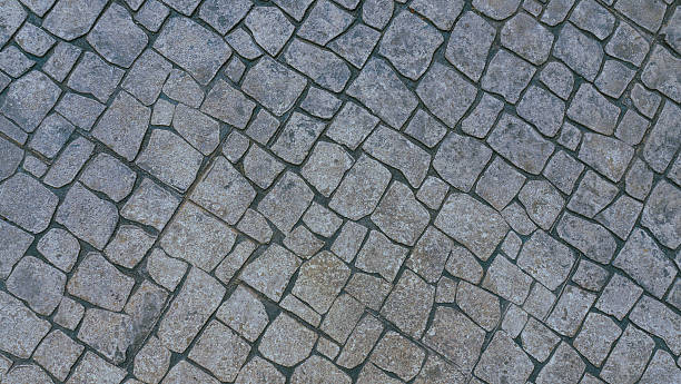 istock Diagonal View of Old Stone Cobblestone Pavement Background 2251850881