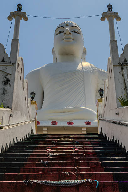 Large white Buddha statue with a long staircase leading up to the monument at Bahirawakanda Temple, overlooking the city of Kandy, Sri Lanka. The sacred site is an important Buddhist landmark, symbolizing spirituality, peace, and cultural heritage in South Asia.