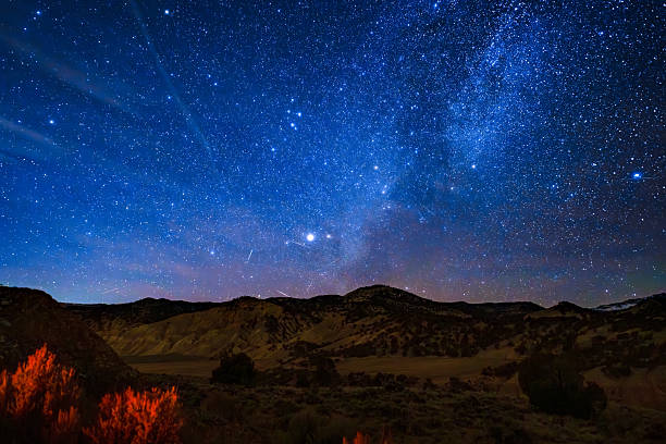 Scenic view of the Flat Tops Mountains in Western Colorado at night with meteors streaking across sky.
