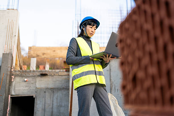 istock Female engineer wearing hard hat working on laptop at construction site 2251855336