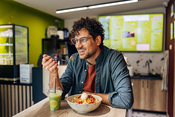 istock Handsome man smiles contentedly as he consumes a high-protein, nutritionally balanced salad and a green superfood smoothie 2251857518