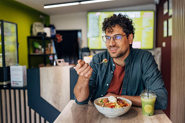 istock Handsome man smiles as he consumes a high-protein, nutritionally balanced salad and a green superfood smoothie 2251857543