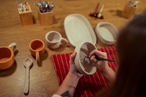 istock Female ceramic artist working on handmade pottery in a cozy studio environment, concentrating on fine details while painting tableware 2251857770