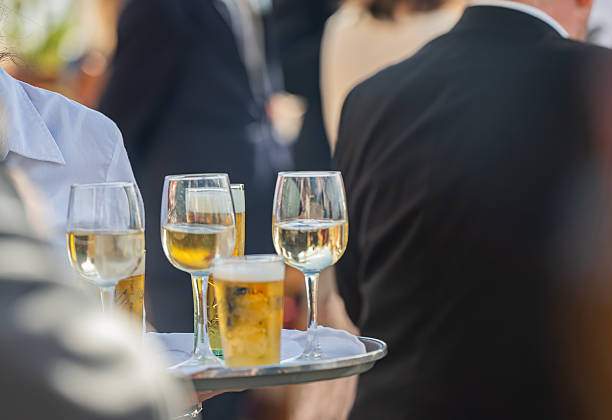 istock Waiter in the foreground with a tray serving professional catering with appetizers and drinks, outdoors. Welcome buffet at the wedding reception. 2251865294