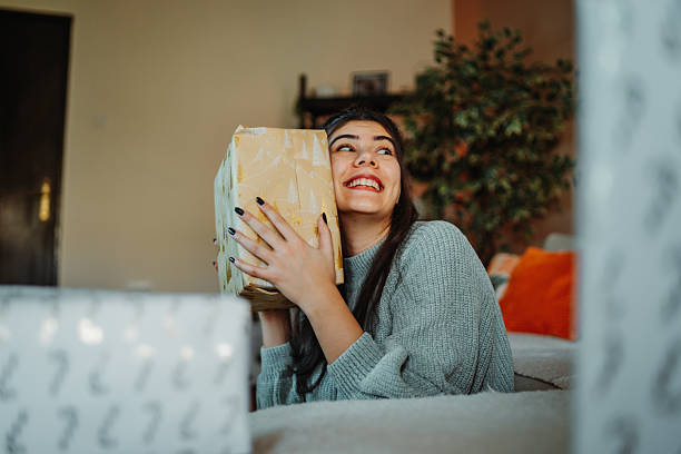 istock Young woman shaking gift box guessing surprise present 2251865324
