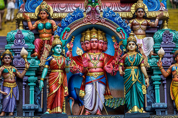 Ornate Hindu temple statues at the entrance of Batu Caves, a famous Hindu temple complex in Malaysia, surrounded by limestone cliffs.