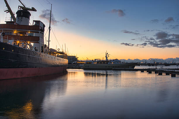 Golden sunset over Lennusadam Harbor in Tallinn featuring historic ships, calm reflective water, and a serene maritime atmosphere at dusk along the Baltic waterfront.