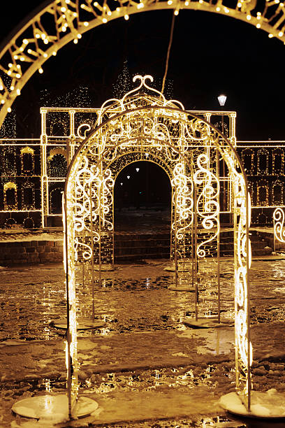 istock Illuminated golden LED light tunnel arches in city park with reflections 2251882252