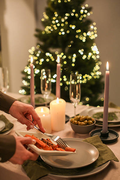 istock Christmas dinner with festive lights and hands serving glazed carrots onto a plate 2251884365