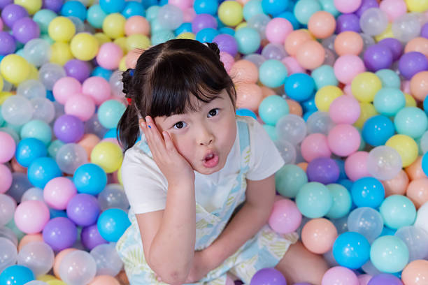 A child lies in a ball pit filled with many colorful balls