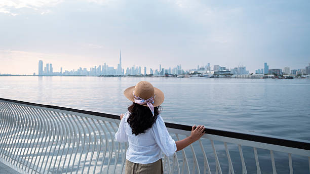 istock a woman walking on a bridge with Dubai skyline background at sunset 2251894121