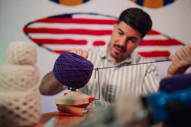 Man winding purple yarn into a tidy yarn cake for knitting or crocheting, focused on his cozy home craft project