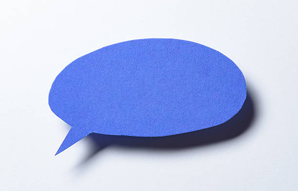 Blue blank cut out paper speech bubble with drop shadow and copy space for text on white background, close-up flat lay top view backdrop