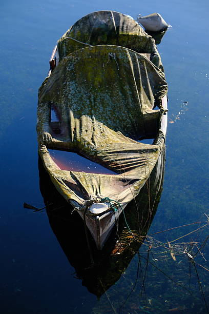 istock Weathered Covered Rowboat Moored on Still Water 2251895783