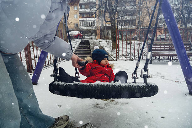 Child on Swing in Winter Playground Snowfall