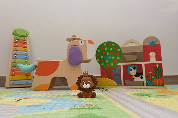 a toy lion in the foreground on a children's rug with other toys in the background