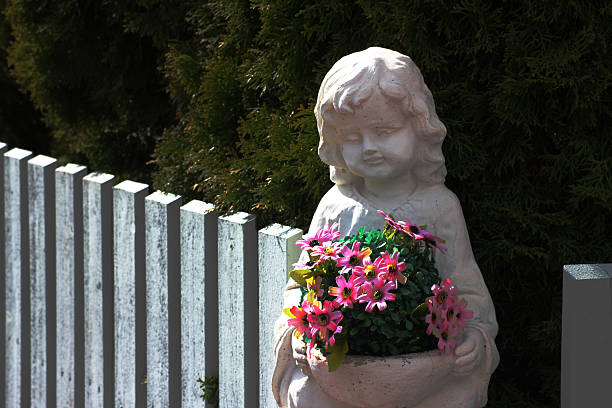 White statue of a woman's head is sitting in a pot. The head is missing its face