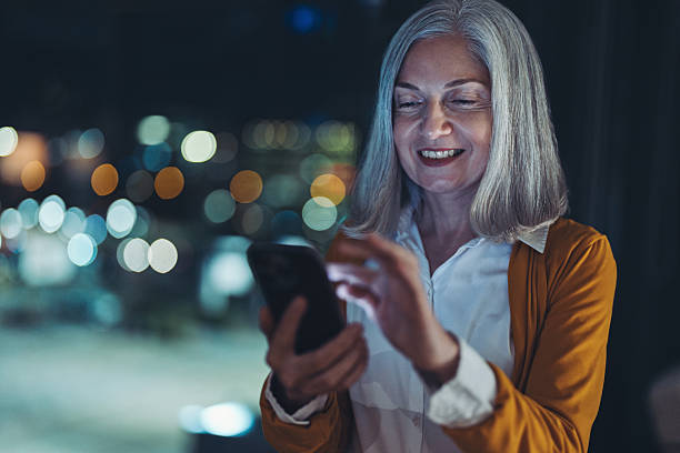 istock Smiling mature woman using phone at night 2251899361