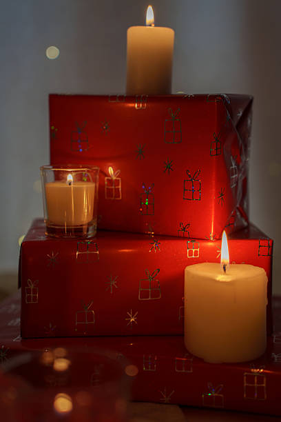 istock a tranquil holiday scene featuring stacked red presents, delicately wrapped with festive designs, softly illuminated by the gentle glow of flickering candles on a cozy winter evening, giftbox, happy 2251902362