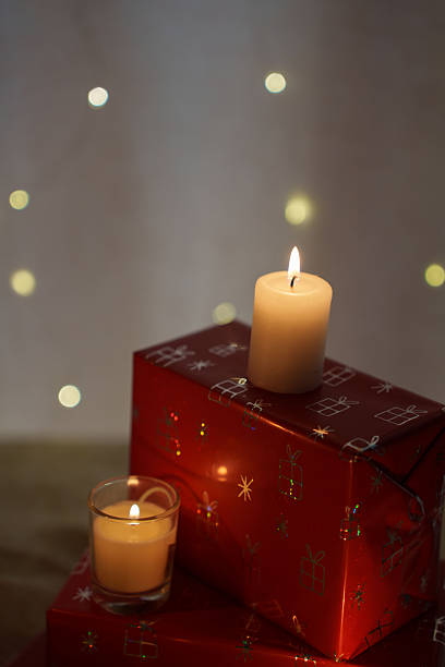 istock cozy holiday scene with illuminated candles on vibrant red gift boxes featuring festive wrapping and softly glowing bokeh lights in a tranquil setting, celebrative, tranquil, quiet, interior 2251902377