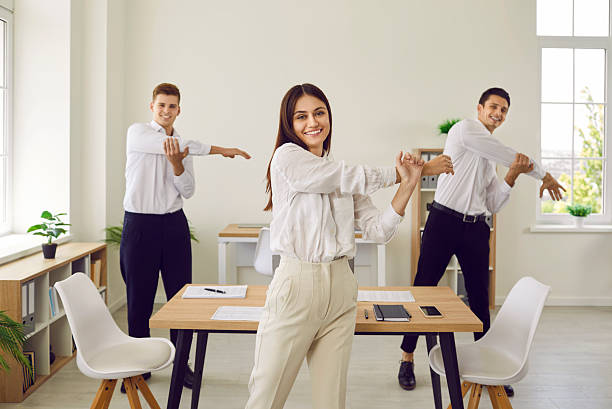 istock Group of smiling young business people doing stretching exercises in office on workplace. 2251903520