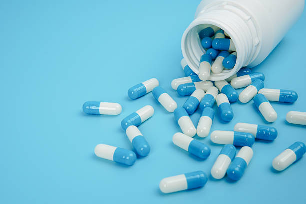 istock Blue and white medicine capsules spilled from bottle representing pharmaceutical supply, healthcare treatment, medication management, and medical industry concept with clean copy space. 2251906593