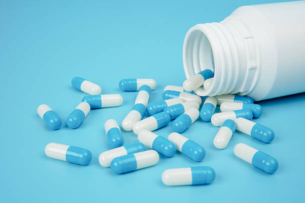 istock Blue and white medicine capsules spilled from bottle representing pharmaceutical supply, healthcare treatment, medication management, and medical industry concept with clean copy space. 2251906595