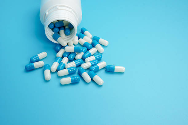 istock Blue and white medicine capsules spilled from bottle representing pharmaceutical supply, healthcare treatment, medication management, and medical industry concept with clean copy space. 2251906627